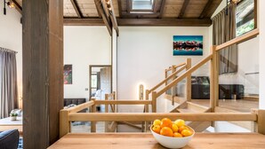 A modern interior with a wooden staircase, a bowl of oranges on a table, and a painting on the wall. - JATOBA - Chalet with a jacuzzi and cinema corner (Chamonix-Mont-Blanc)