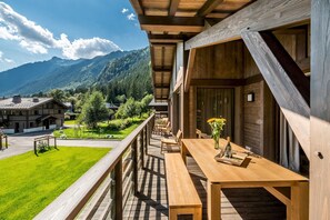 Une terrasse en bois avec une table et des chaises, offrant une vue sur un paysage montagneux.