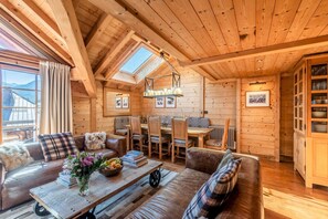 A cozy wooden cabin interior with a dining area, sofa, and a table with books and flowers. - GARAPA - Apartment in the heart of Morzine (Morzine)