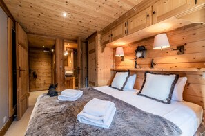 A wooden cabin bedroom with a large bed, two bedside lamps, and a fur throw. - GARAPA - Apartment in the heart of Morzine (Morzine)