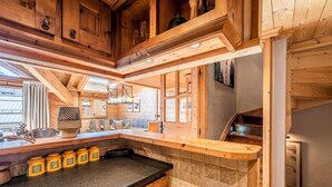 Une cuisine en bois avec un plan de travail noir, des placards en bois et un pare-feu en carreaux.