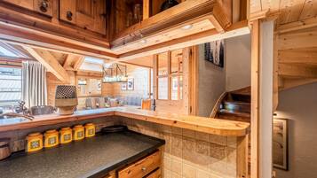 Una cucina in legno con piano di lavoro nero, mobili impiallacciati e zoccolo piastrellato.