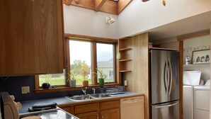Une cuisine moderne avec des meubles en bois, un réfrigérateur en acier inoxydable et une grande fenêtre donnant sur l’extérieur.