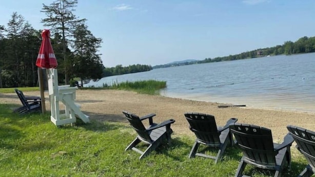 Un cadre agréable au bord du lac, avec des sièges en plein air et un parasol rouge.