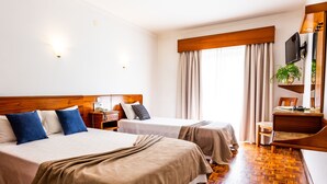 A hotel room with two beds, a TV, a desk, and a chair. - Dona Amélia Hotel by RIDAN Hotels (Ourem)