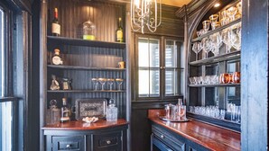 A bar area with shelves of bottles, glasses, and a wine rack. - Southern Elegance in Heart of Memphis (Memphis)