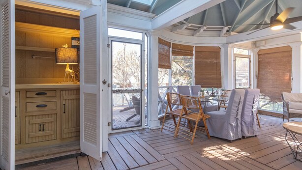 A covered patio with wooden flooring, a dining area with chairs and a table, and a kitchen area with cabinets and a lamp. - Southern Elegance in Heart of Memphis (Memphis)