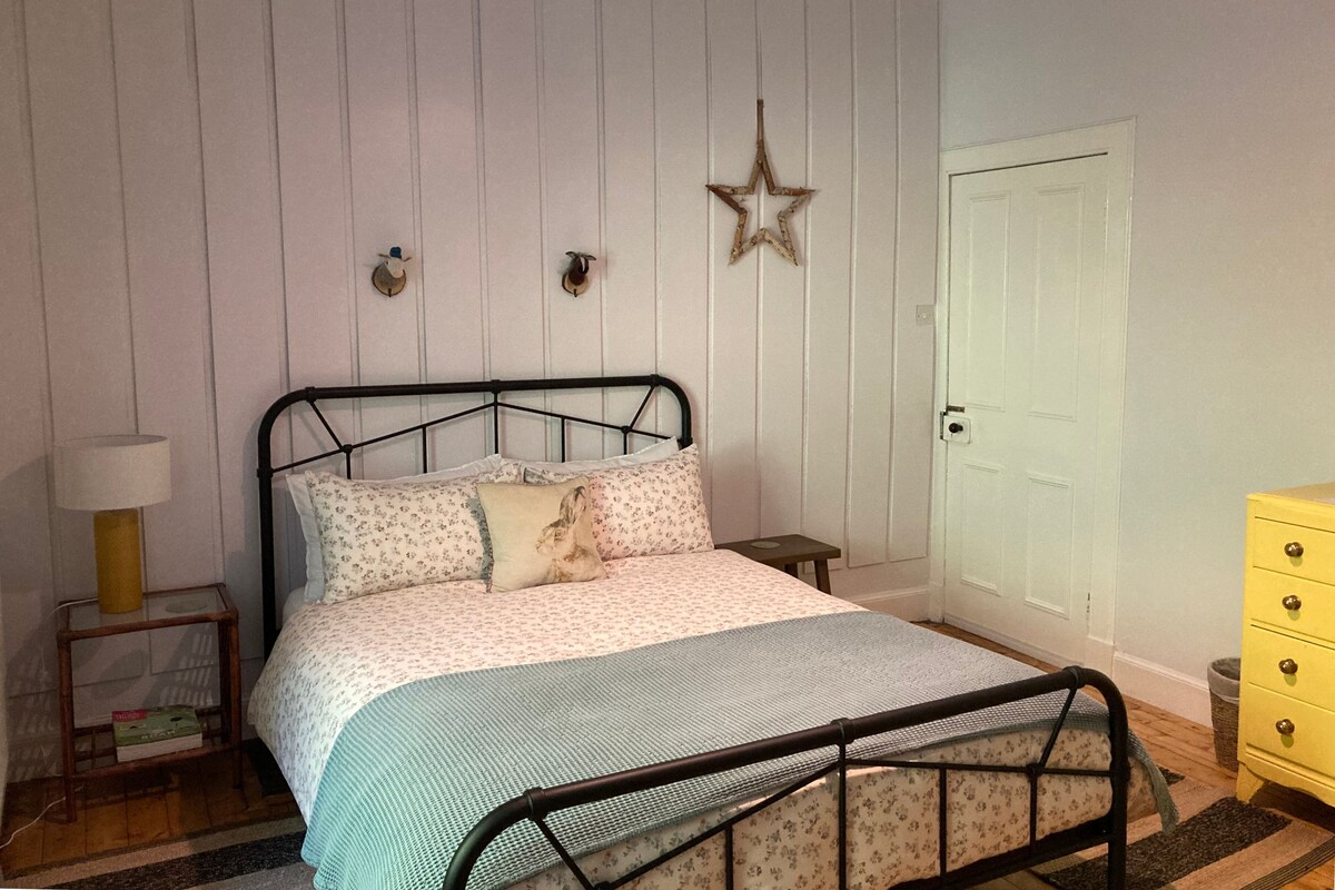 Un dormitorio con cama, mesita de noche, cómoda y decoración con estrellas, además de una puerta.