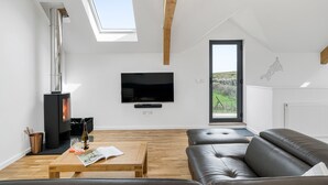 A modern living room with a fireplace, a flat-screen TV, a sofa, and a wooden coffee table. - Perfect for a Cornish getaway, Cedar House is located just outside the hustle and bustle of St Agnes (St Agnes)
