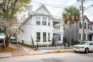 Une maison blanche à deux étages, dotée d’un balcon, d’un garage et d’une allée.