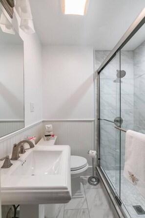 Une salle de bain moderne avec une douche à parois de verre, un lavabo blanc et des toilettes.