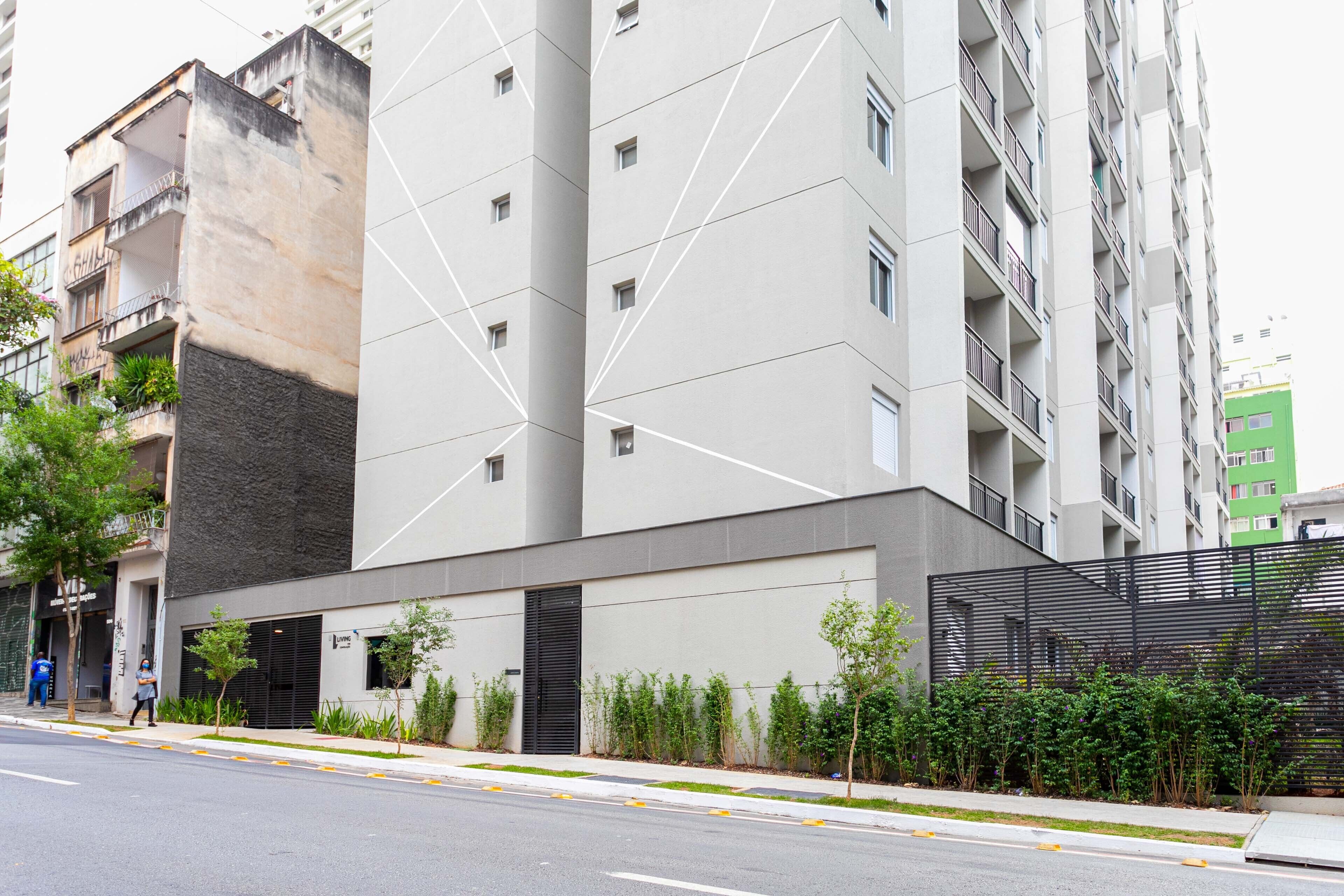 A modern multi-story building with a geometric facade, balconies, and a gated entrance.