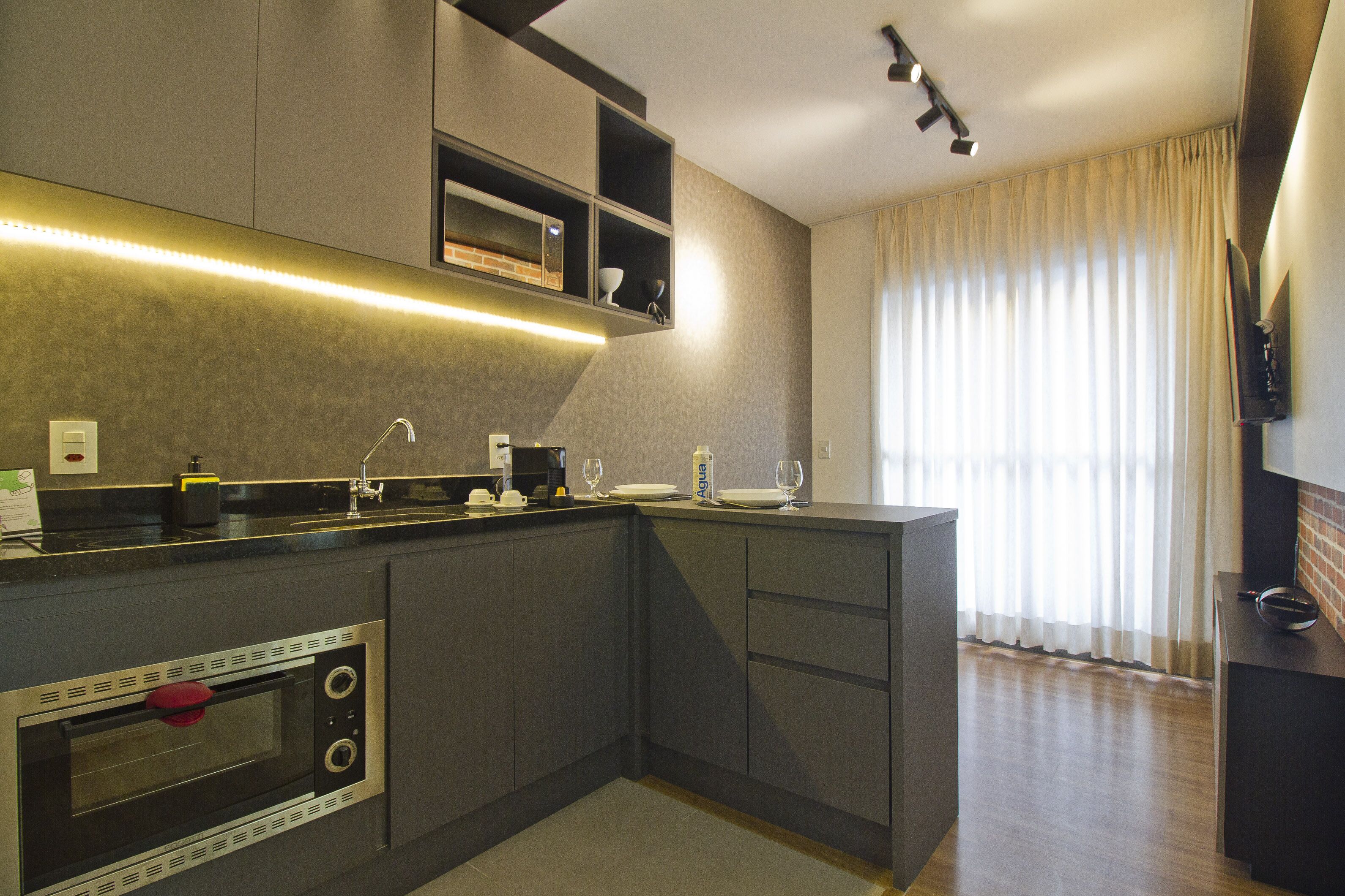 Una cocina moderna con electrodomésticos integrados, una encimera y un amplio ventanal con cortinas.