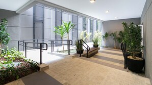 Un espacio interior moderno con una escalera, plantas en macetas y un amplio ventanal que proporciona luz natural.