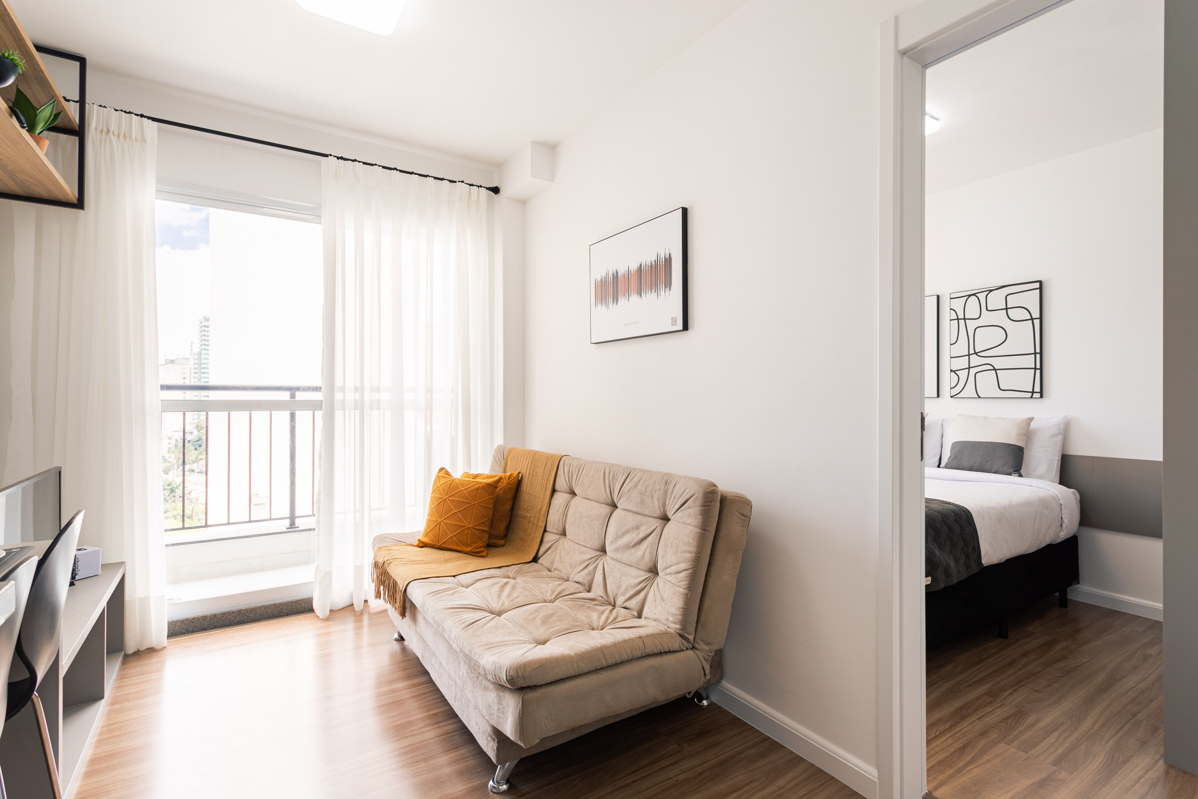 Ein modernes Schlafzimmer mit Schlafsofa, Schreibtisch und Balkon.