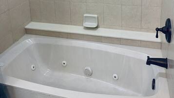 Une salle de bain équipée d’une baignoire, d’un porte-savon et d’un sèche-mains fixé au mur.