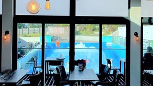Un restaurant doté de grandes fenêtres, de luminaires suspendus et d’une terrasse.