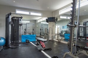 Une salle de sport équipée de divers appareils d’entraînement, notamment un support à squats, des bancs et des poids.