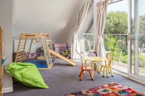 Un espace de jeux pour enfants avec un toboggan, une structure d’escalade et une table avec des chaises.