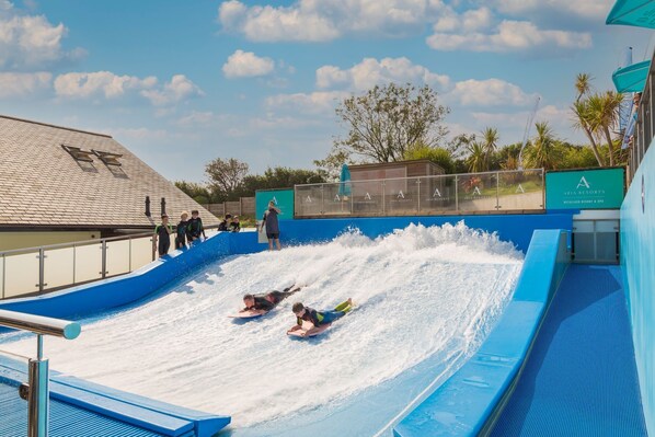 Une toboggan aquatique dans un complexe hôtelier, avec un ciel dégagé et des palmiers en arrière-plan.