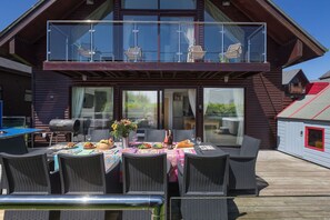 Une cabane en bois dotée d’un balcon, d’un espace repas extérieur et offrant une vue sur le paysage environnant.