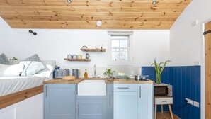 Une cuisine de taille réduite avec un plafond en bois, une petite fenêtre et un four à micro-ondes posé sur un meuble en bois.