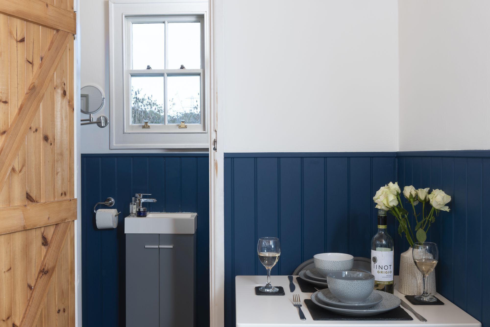 A kitchen with a sink, a window, and a dining area with a table set for two.