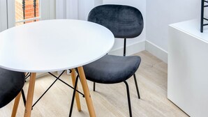 Un comedor moderno con una mesa redonda blanca, dos sillas negras y patas de madera.