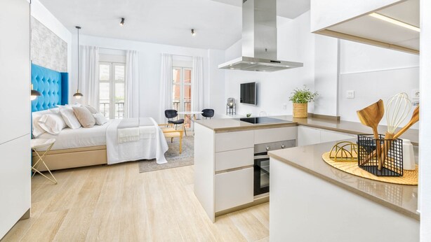 Una cocina moderna con una isla central, horno empotrado y un amplio ventanal.