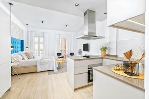 Une cuisine moderne dotée d’un îlot central, d’un four encastré et d’une grande fenêtre.