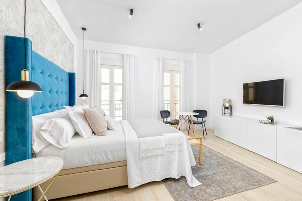 Une chambre moderne avec un grand lit, un bureau et une télévision.