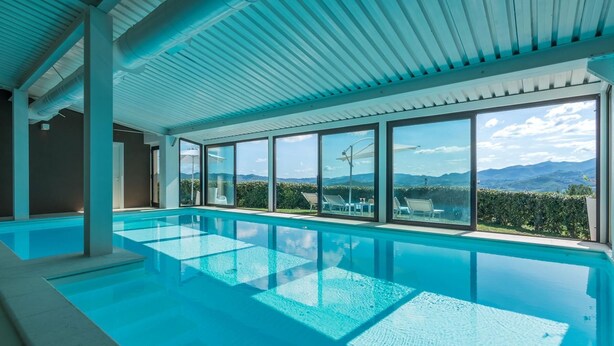 Ein Hallenbad mit Glaswänden und Blick auf Berge.