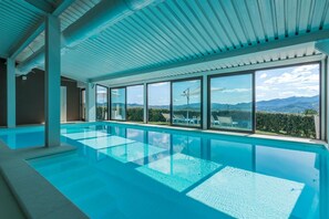 Piscina interior con paredes de vidrio transparente y vistas a montañas.
