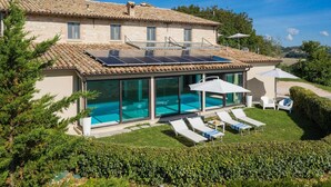 Ein Haus mit Schwimmbad, Solaranlage und Sitzgelegenheit im Freien.