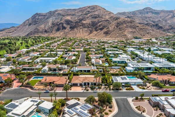 A residential area with houses, roads, and mountains in the background.