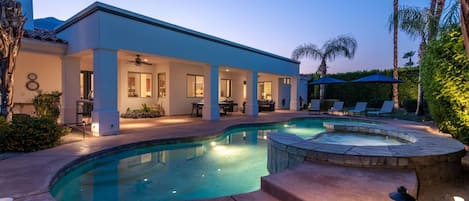 A modern house with a swimming pool, outdoor seating, and a covered patio area.