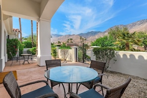 Relax in a serene outdoor space with a round table and wicker chairs, surrounded by breathtaking views of the landscape.
