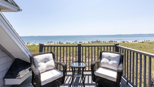 A balcony with wicker furniture and a glass table overlooking a beach. - Spectacular Oceanfront Property Offering Bold Panoramic Views of Saco Bay ! (Old Orchard Beach)