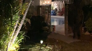 A nighttime view of a garden area with a pathway leading to a building entrance. - Pineapple Cove-Adorable Home W/ Private Tropical Pool/ close to Beach & Park (North Palm Beach)