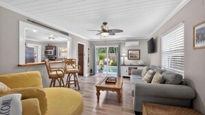 A living room with a sofa, a coffee table, and a dining area with chairs. - Pineapple Cove-Adorable Home W/ Private Tropical Pool/ close to Beach & Park (North Palm Beach)