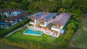 A modern two-story house with a swimming pool, solar panels, and a well-maintained garden. - Sophisticated Villa with Fairway Views & Private Pool, Close to the Beach (Tamarindo)