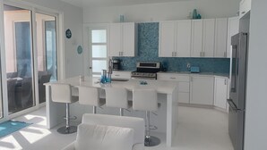 A modern kitchen with white cabinets, a blue backsplash, and a stainless steel refrigerator.