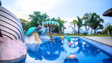 Una piscina con tobogán, una escultura de tortuga y una escultura de tiburón.