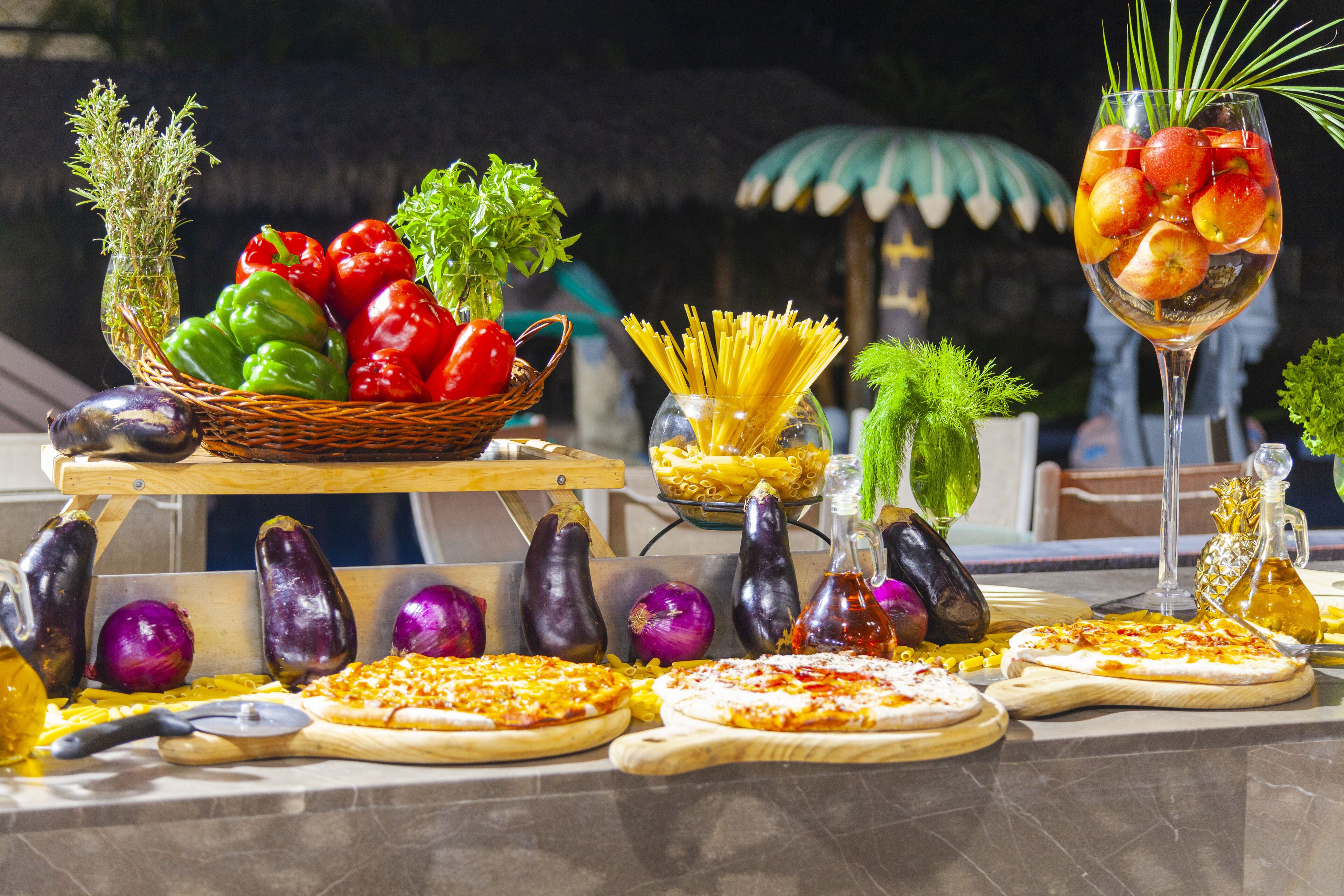A table with various food items including pizzas, vegetables, and a drink.