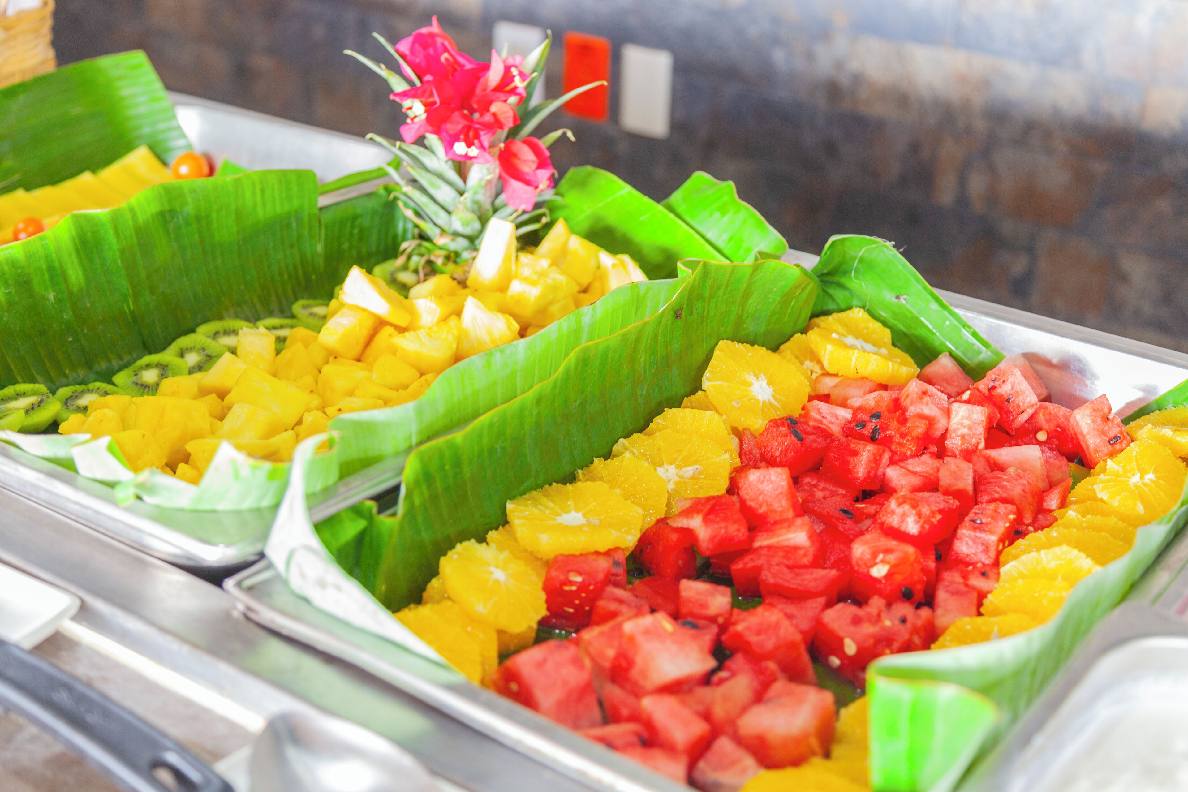 A buffet with various fruits arranged in banana leaves.