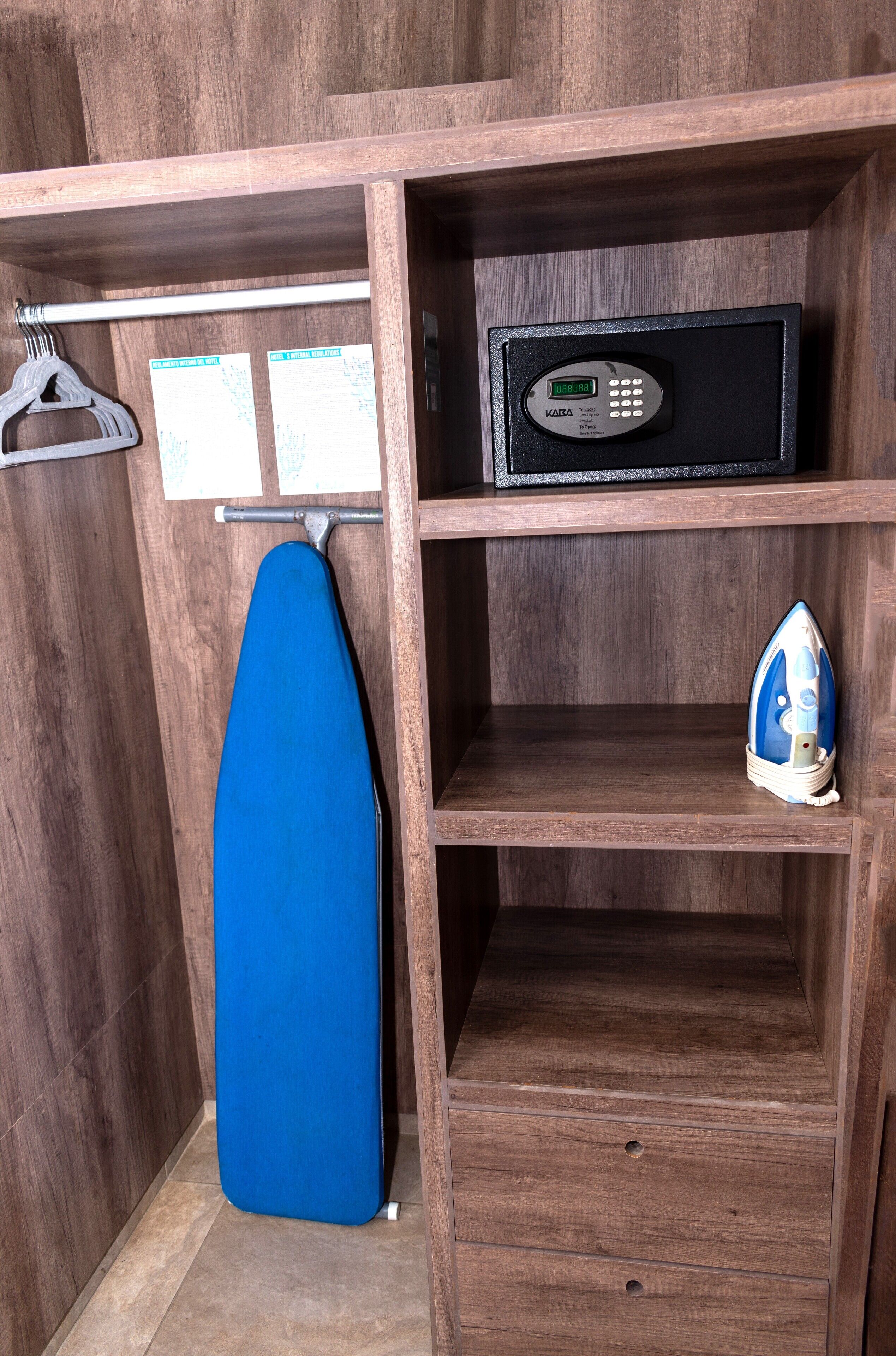 Un armario de madera con una tabla de planchar azul, un planchador pequeño y un candado digital.