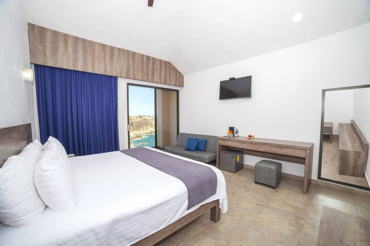 Une chambre d’hôtel moderne équipée d’un grand lit, d’un bureau, d’un canapé et d’une télévision.