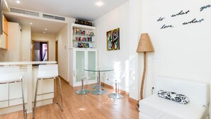 Een moderne woonkamer met een witte bank, een glazen salontafel en een witte boekenkast.