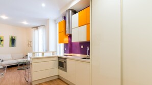 Een compacte keuken met een inbouwoven, een spoelbak en een rvs afzuigkap.