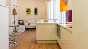 Een moderne keuken met een inbouwoven en een eethoek met een glazen tafel en stoelen.